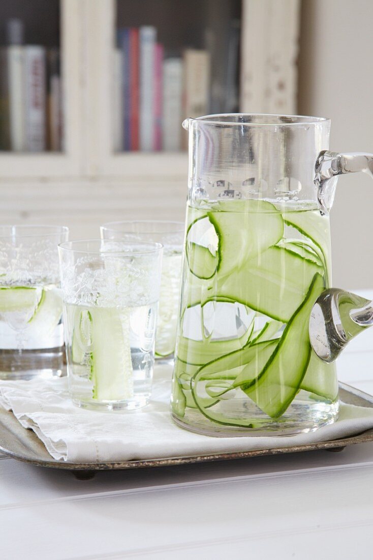 Water with cucumber strips in a carafe and in glasses