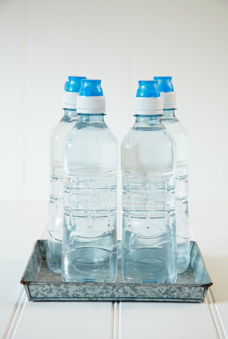 Four bottles of water on a metal tray