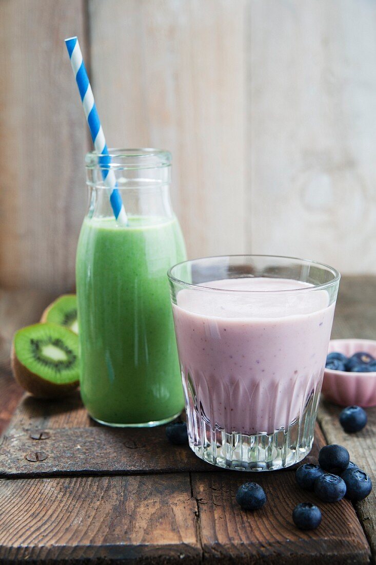 Grünkohl-Apfel-Smoothie in Glasflasche und Blaubeer-Bananen-Smoothie im Glas