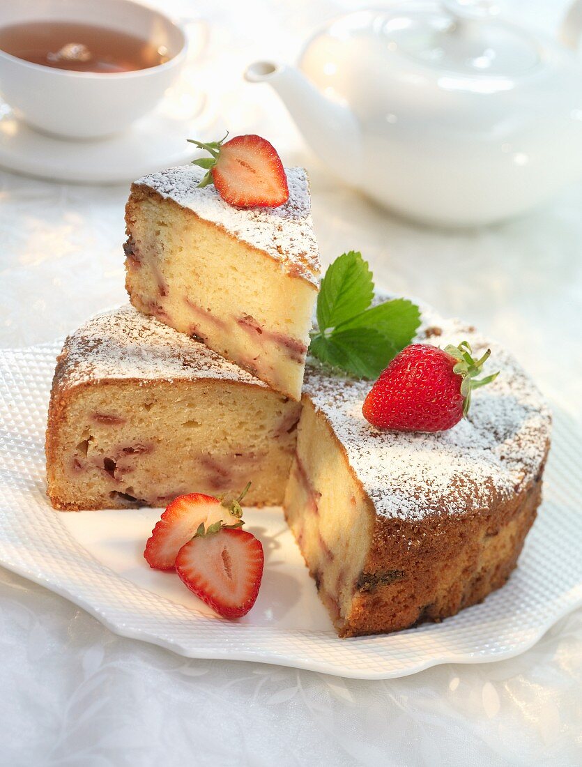 Madeira cake with strawberries and icing sugar, sliced