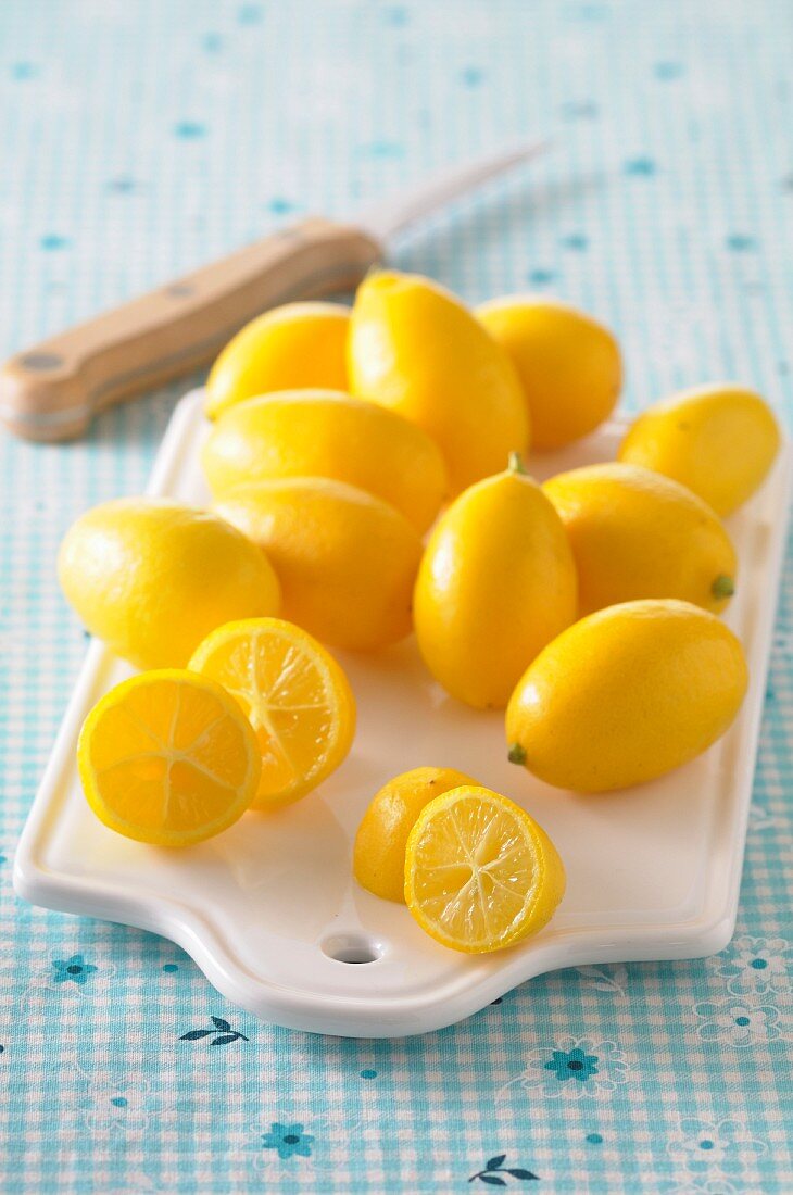 Mini-Zitronen auf Porzellanbrett mit Messer