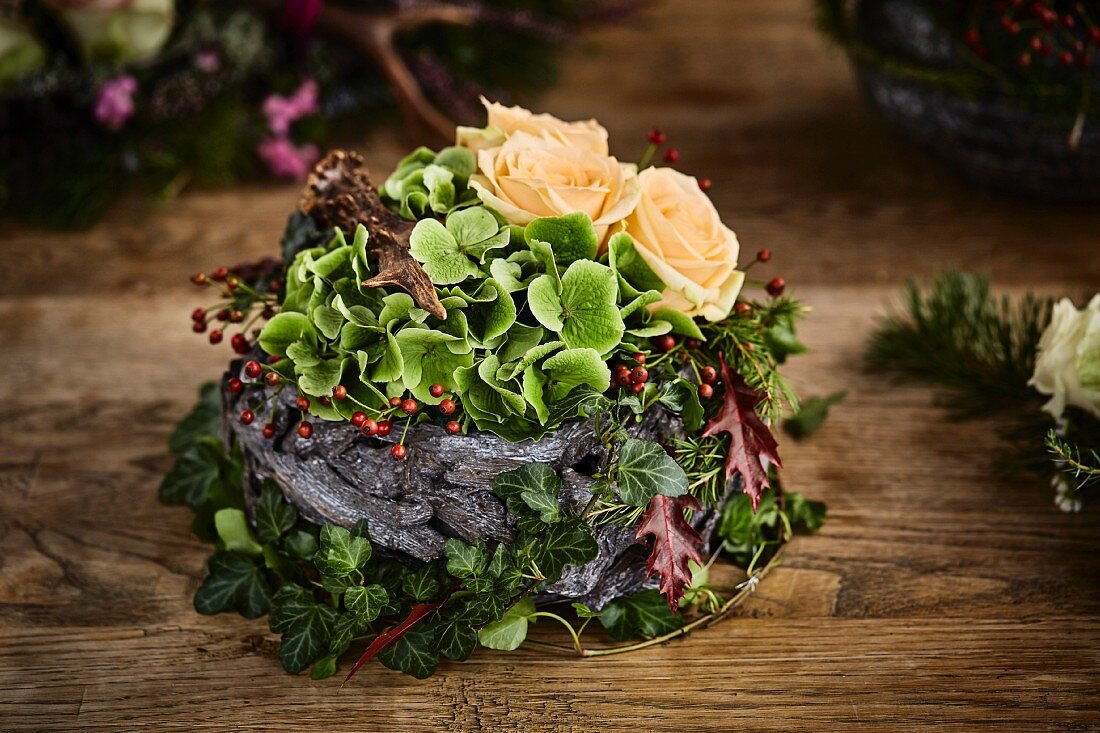 Rosengesteck im alpinen Stil mit cremeweissen Rosen, Hortensien und Holzrinde