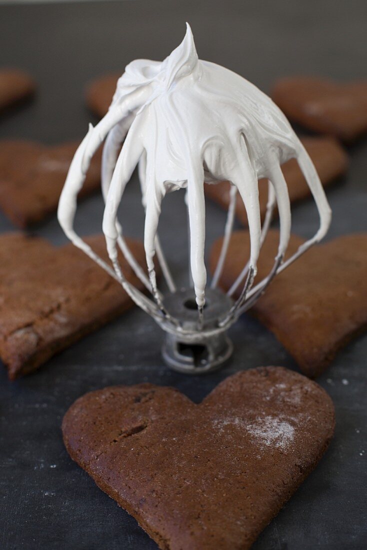 Gingerbread hearts and a whisk with an icing sugar-egg white glaze