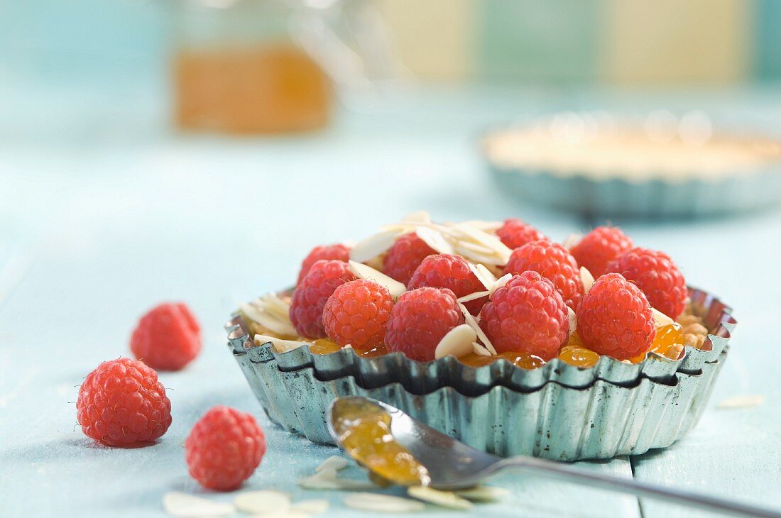 A raspberry tartlet with slivered almonds and jam