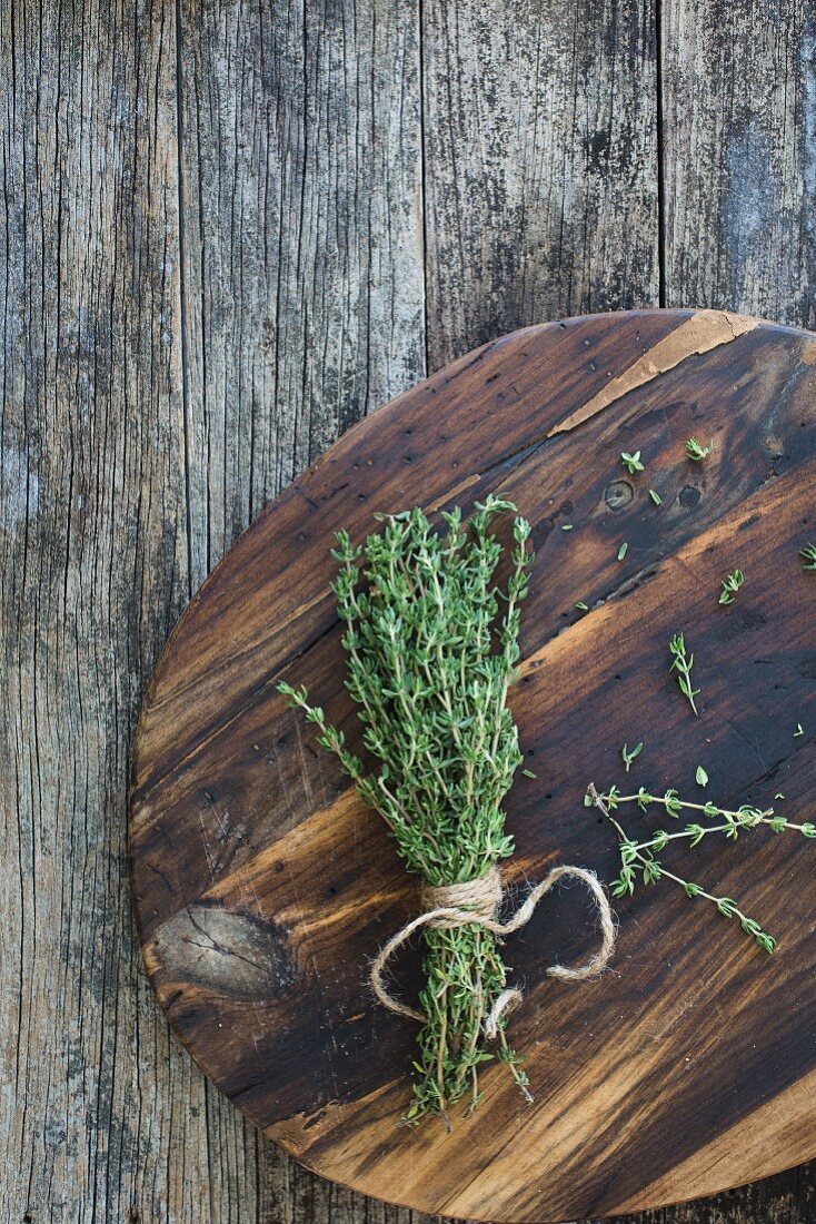 A bundle of fresh thyme on a wooden plate