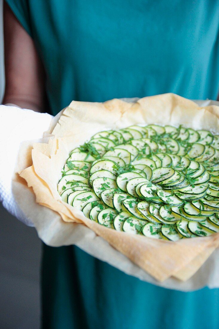 Frau mit ungebackener Zucchiniquiche