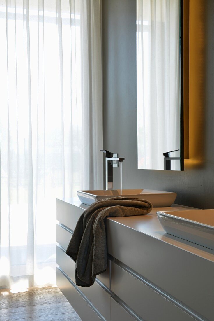 Custom washstand below mirror with integrated lights in elegant designer bathroom