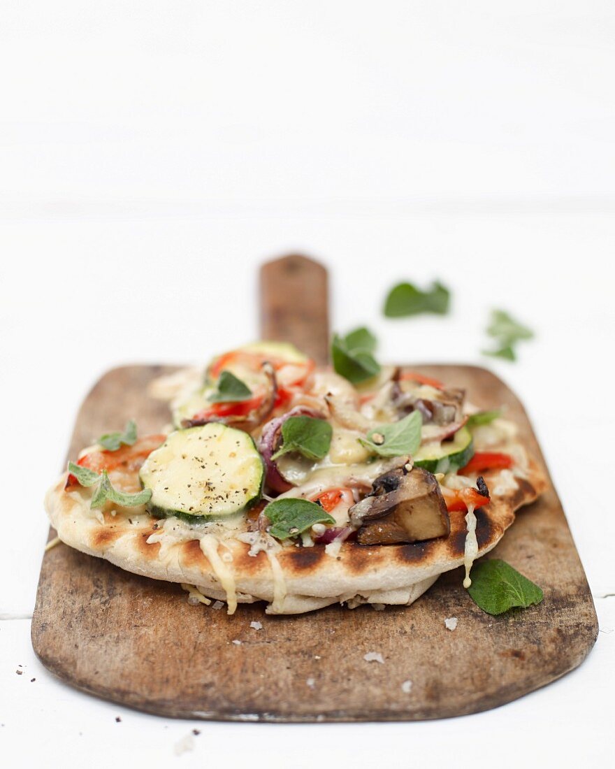 A mini vegetable pizza on a wooden board