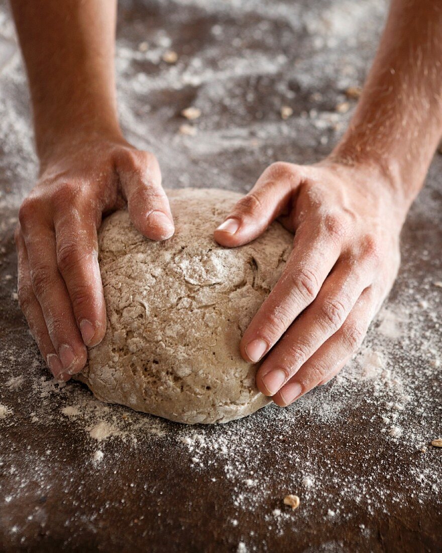 Mann bäckt ein Laib Roggenbrot