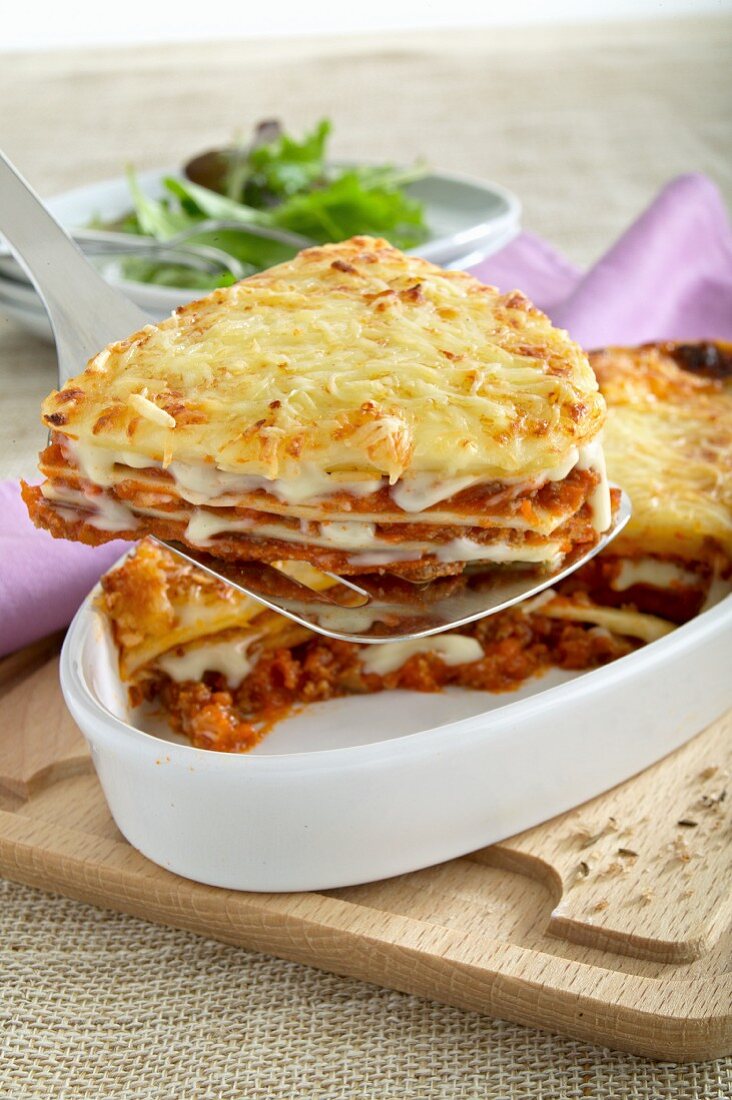 A slice of lasagne being removed from the baking dish