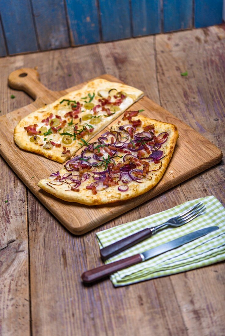 Tarte flambée with two different toppings on a chopping board