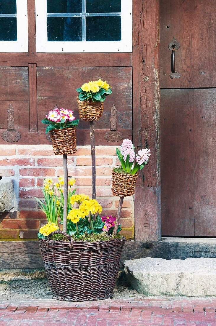 Rustic arrangement of spring flowers and wicker baskets next to front door