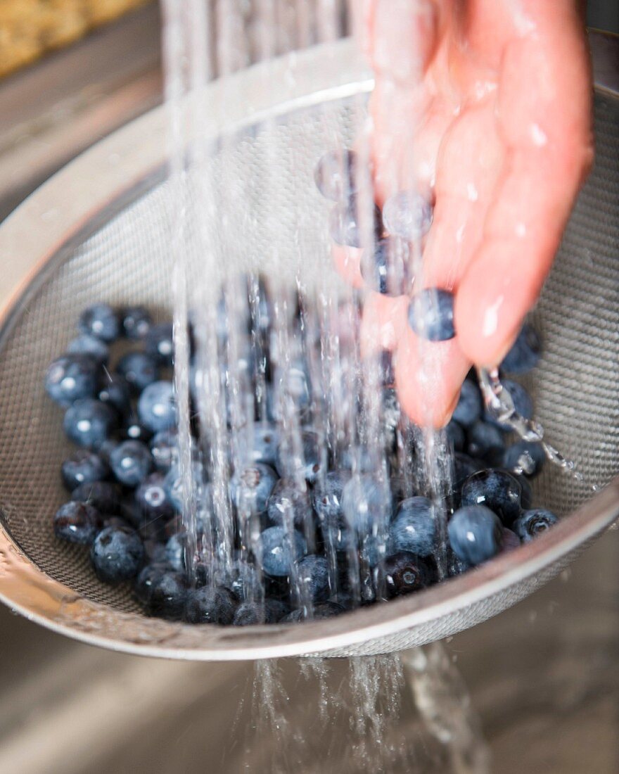 Blueberries being washed in a sieve