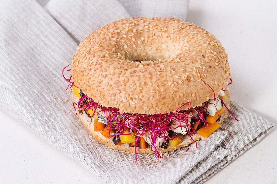 A bagel with carrots, blue cheese and beetroot sprouts