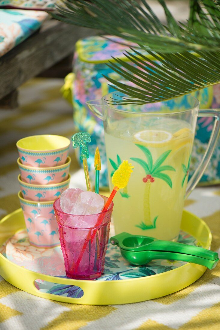 Colourful beakers and jug of refreshing drink on tray