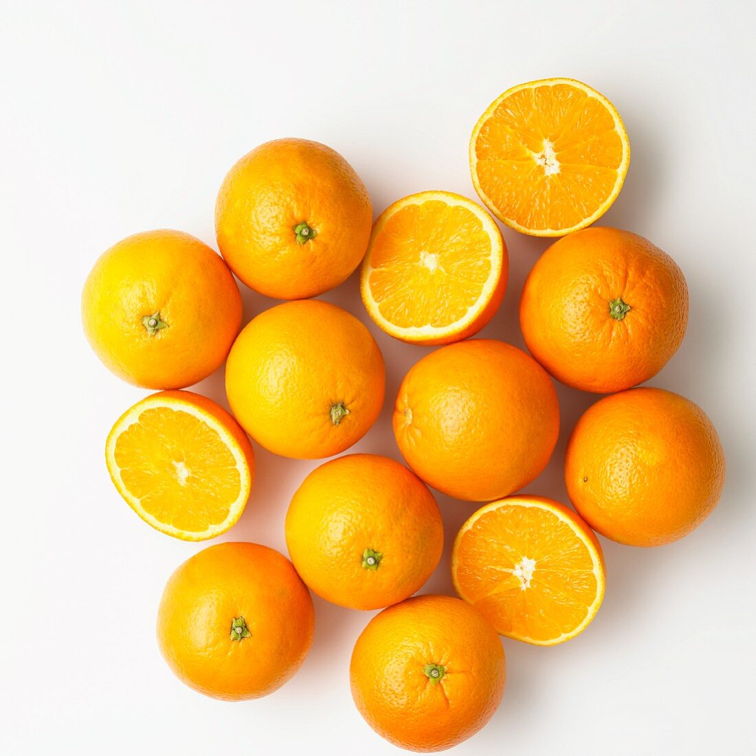 Oranges, whole and halved on a white surface (seen from above)