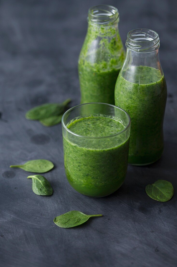 Grüner Spinatsmoothie in Glas und Flaschen