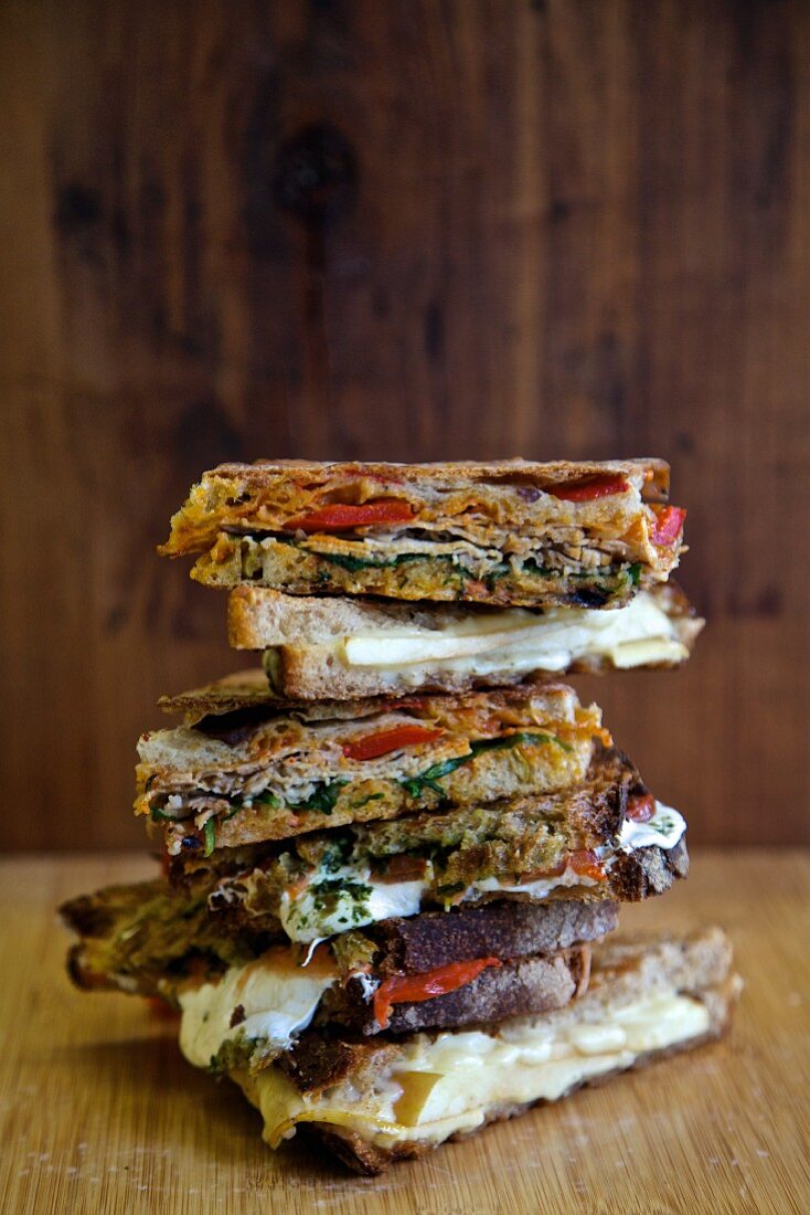 A stack of various grilled sandwiches to take away