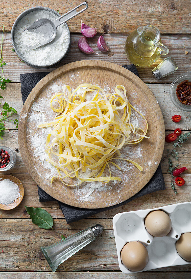 Frische ungekochte Tagliatelle auf Holzteller