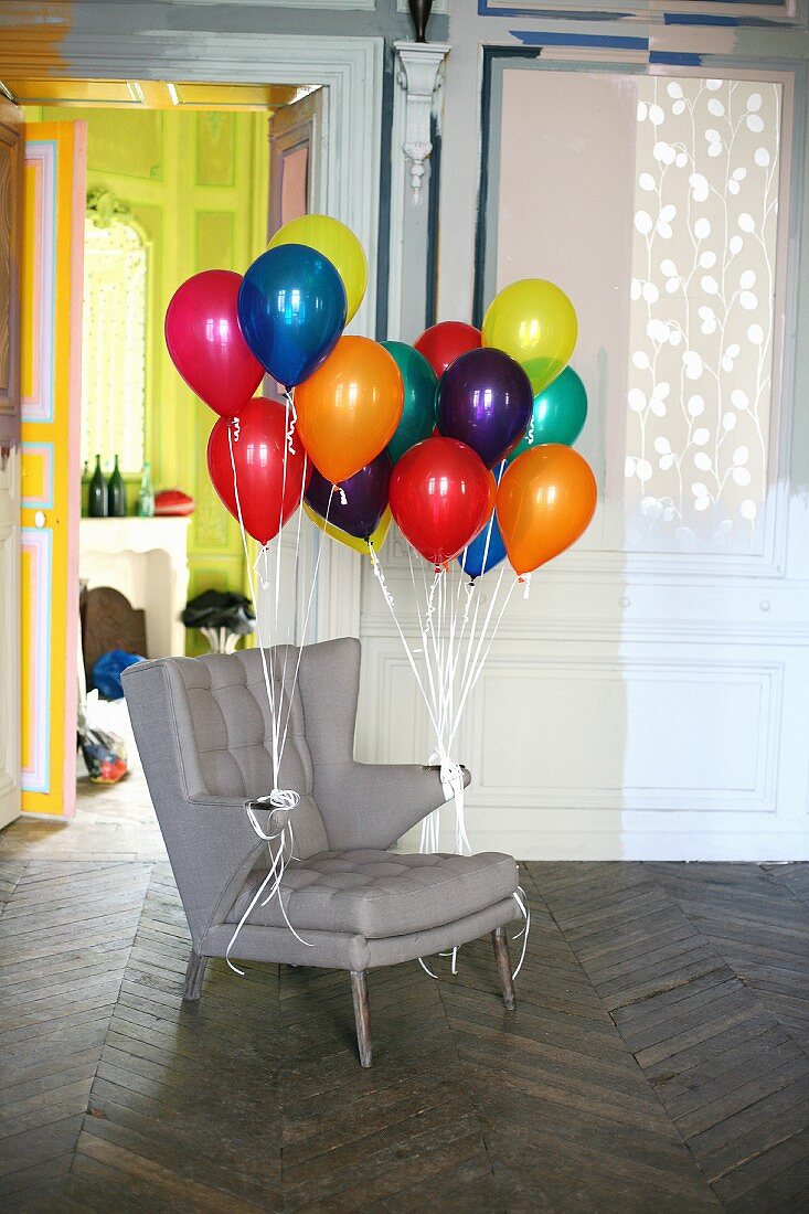 Zwei Bündel Luftballons an Armlehnen eines Sessels