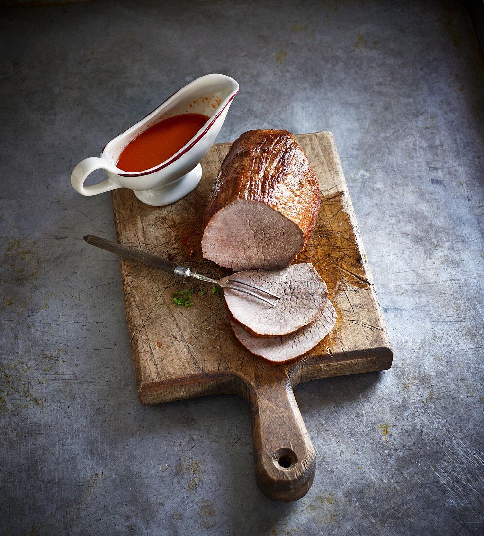 Roast beef with tomato sauce on a wooden board
