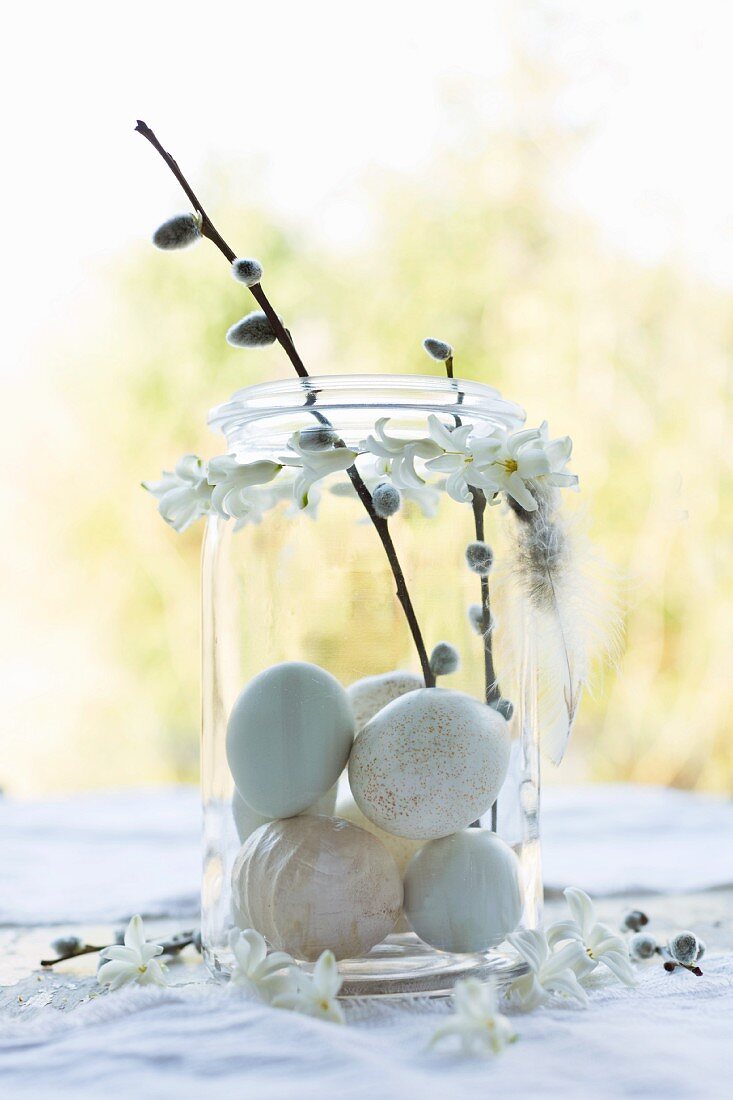 Helle Eier in einem Weckglas mit Weidenkätzchen-Zweigen und Girlande aus Hyazinthenblüten