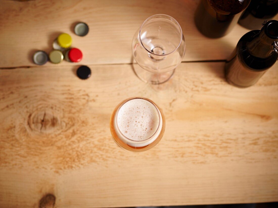 Beer glasses, beer bottle caps and beer bottles on a wooden surface