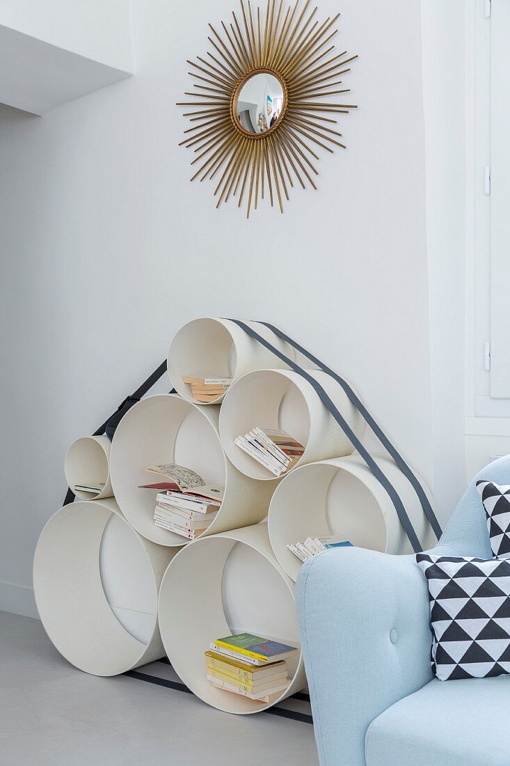 Shelves made from pipes of various diameters below gilt sunburst mirror