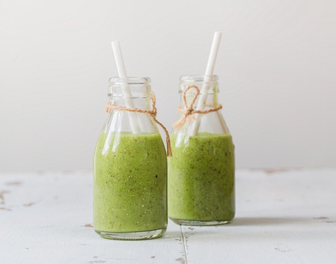 Green smoothies with avocado, kiwi, spinach, ginger and chia seeds in bottles