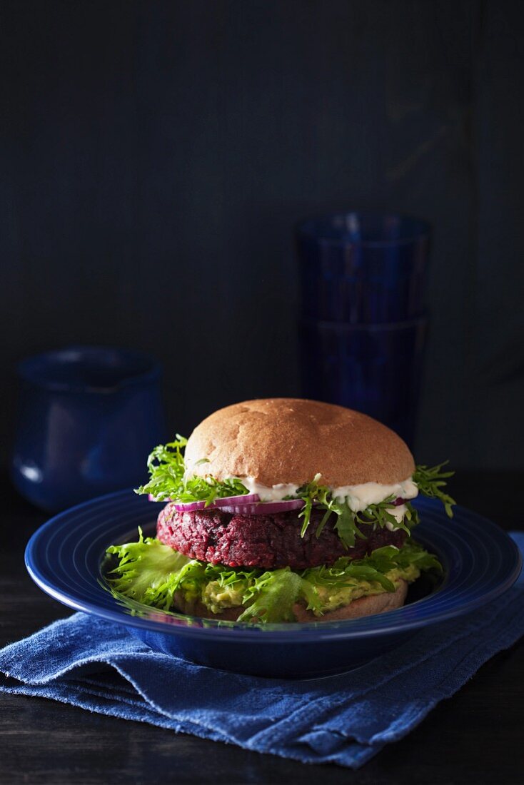 A veggie burger with a beetroot patty, avocado spread and vegan sauce