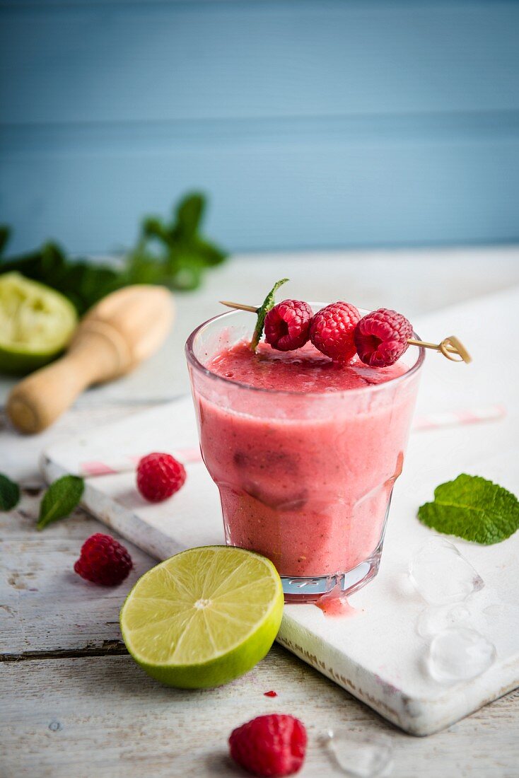 Ein Glas Smoothie, garniert mit frischen Himbeeren und Minze