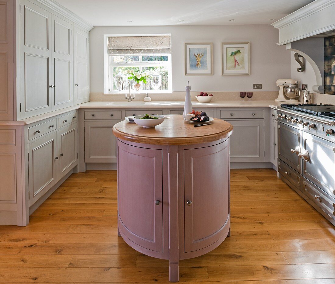 Pastel panelled cabinet doors, island counter and vintage-style cooker in rustic kitchen