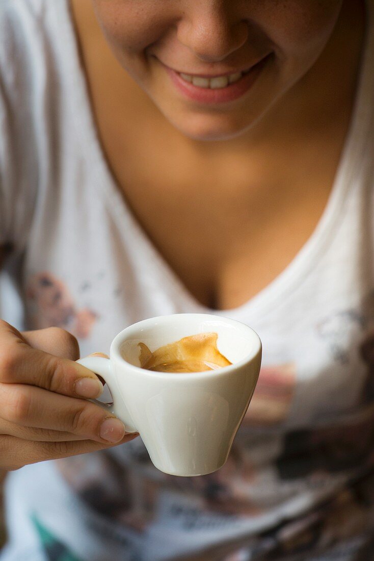 A woman holding an espresso cup at the 'Orso Laboratorio Caffè' in Berthollet street, Turin, Italy