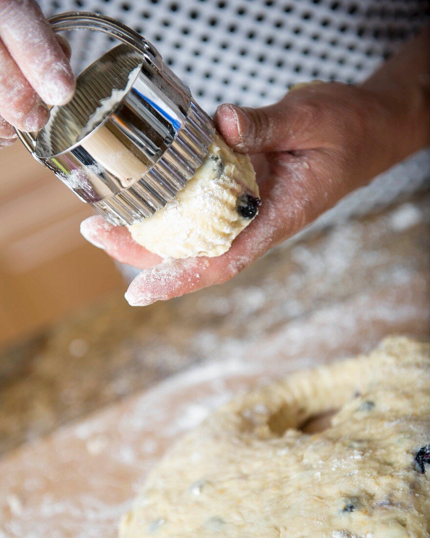 A raw scone being remove from a cutter