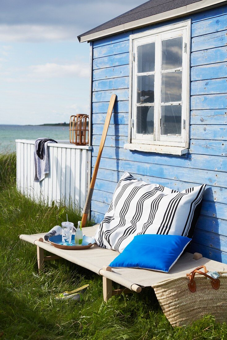 Camp bed outside blue beach hut