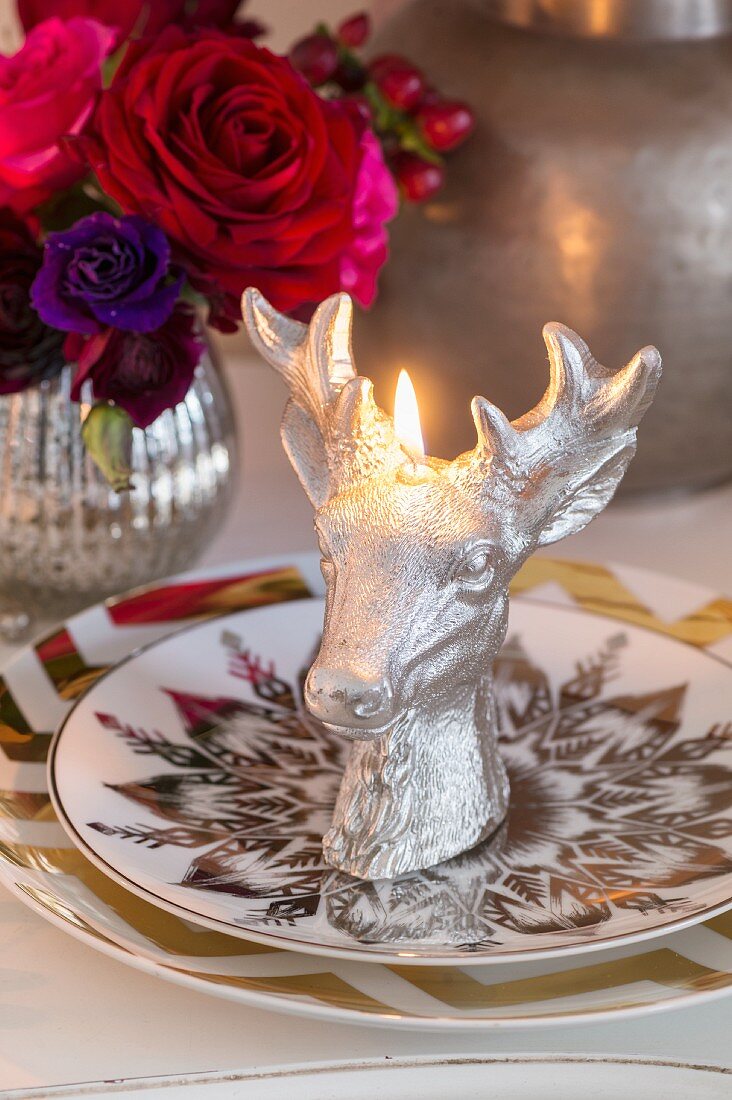 Lit, stags-head candle on plates with gilt patterns