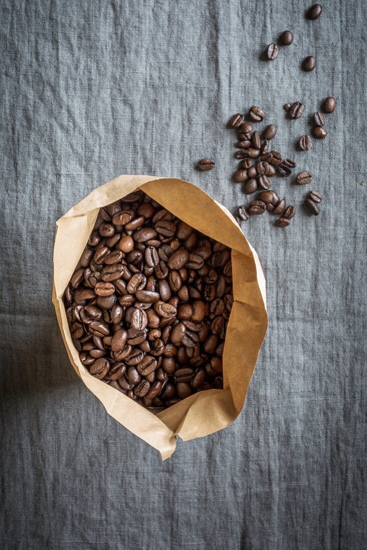Coffee beans in a paper bag on a grey linen cloth
