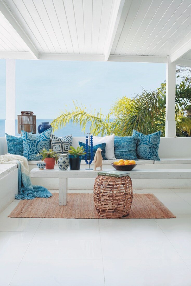 Scatter cushions with variously patterned blue covers on bench on summery veranda