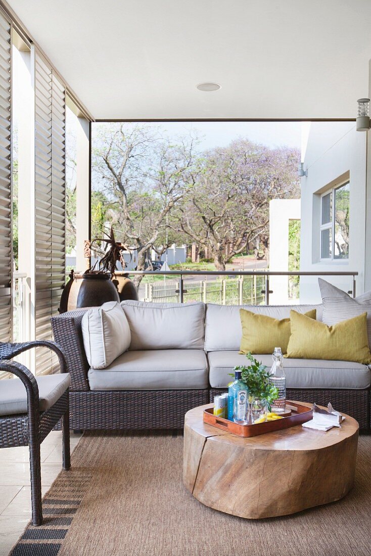 Sofa and slice of tree trunk used as coffee table on veranda