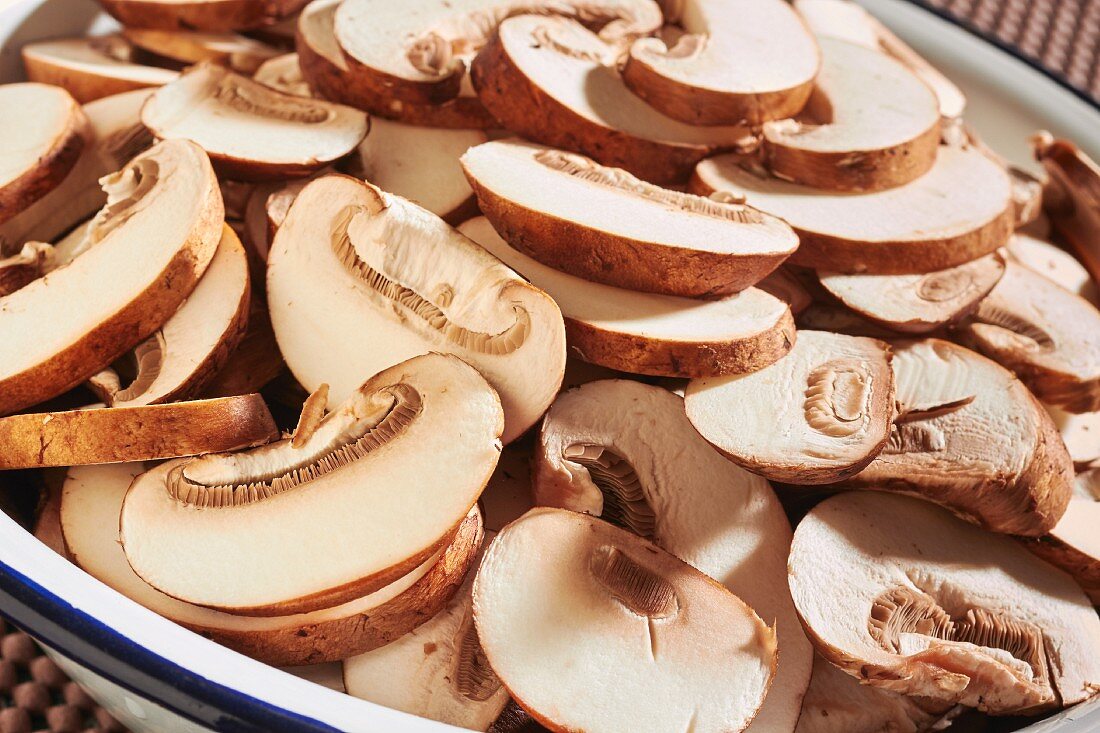 Sliced, fresh brown mushrooms in an enamel bowl