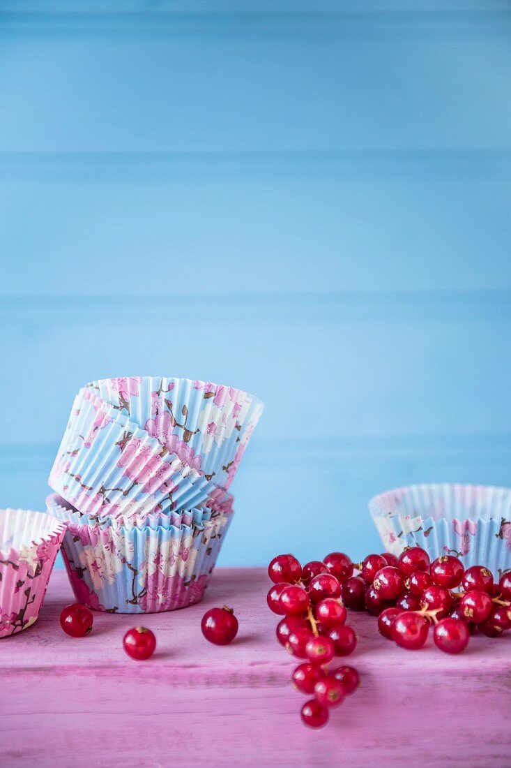 Frische rote Johannisbeeren und leere Cupcakeförmchen