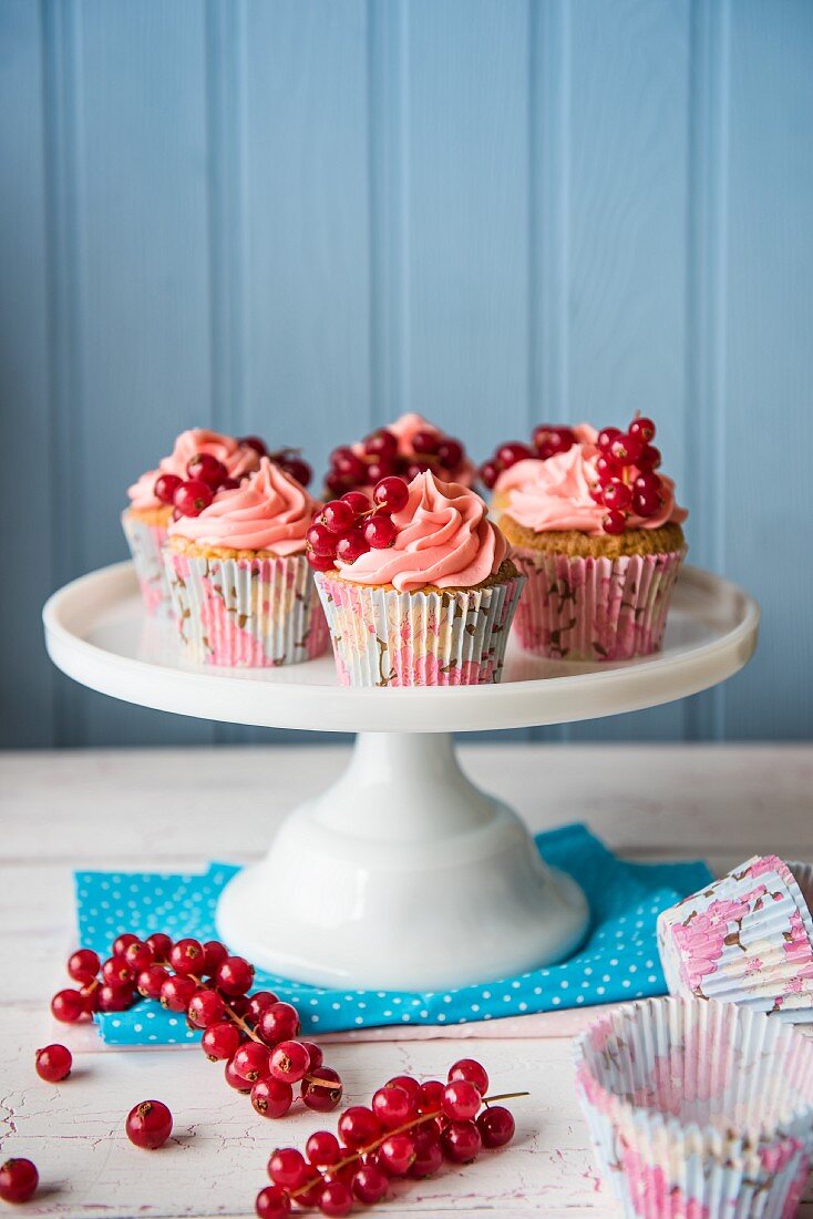 Cupcakes with pink cream and fresh redcurrants on a cake stand