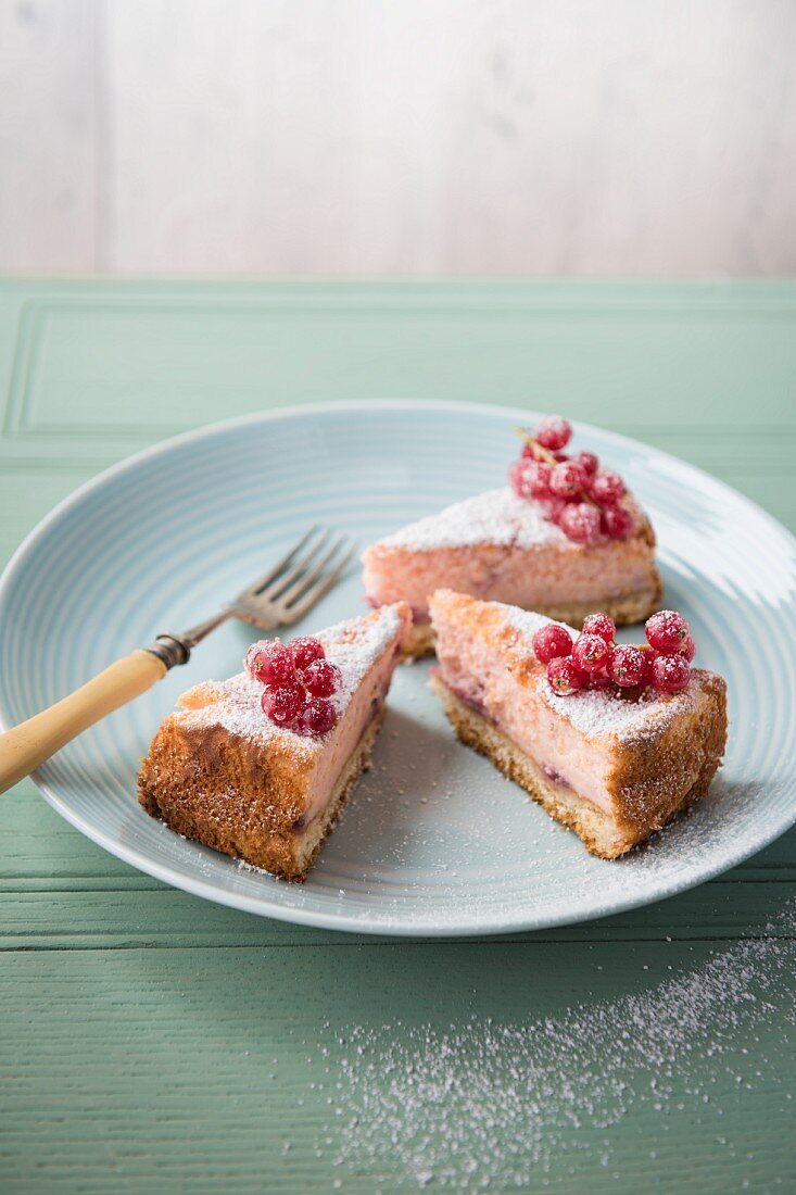 A three slices of sugared redcurrant cheesecake on a plate.