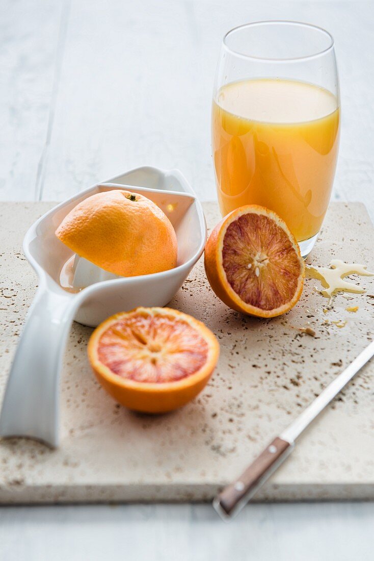 Frisch gepresster Orangensaft im Glas und halbierte Orangen