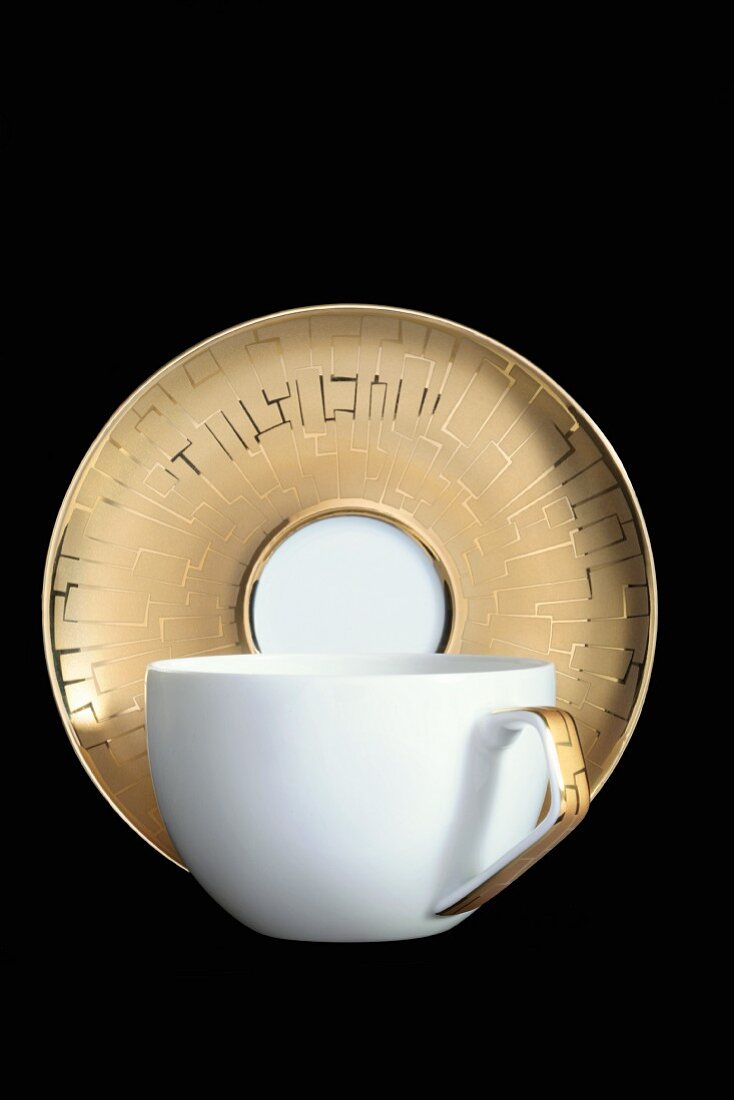 A white espresso cup with a golden saucer