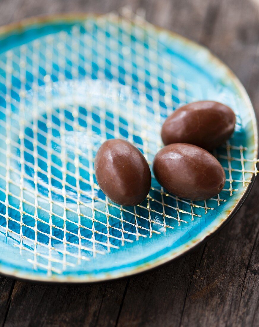 Three small chocolate eggs on a blue plate