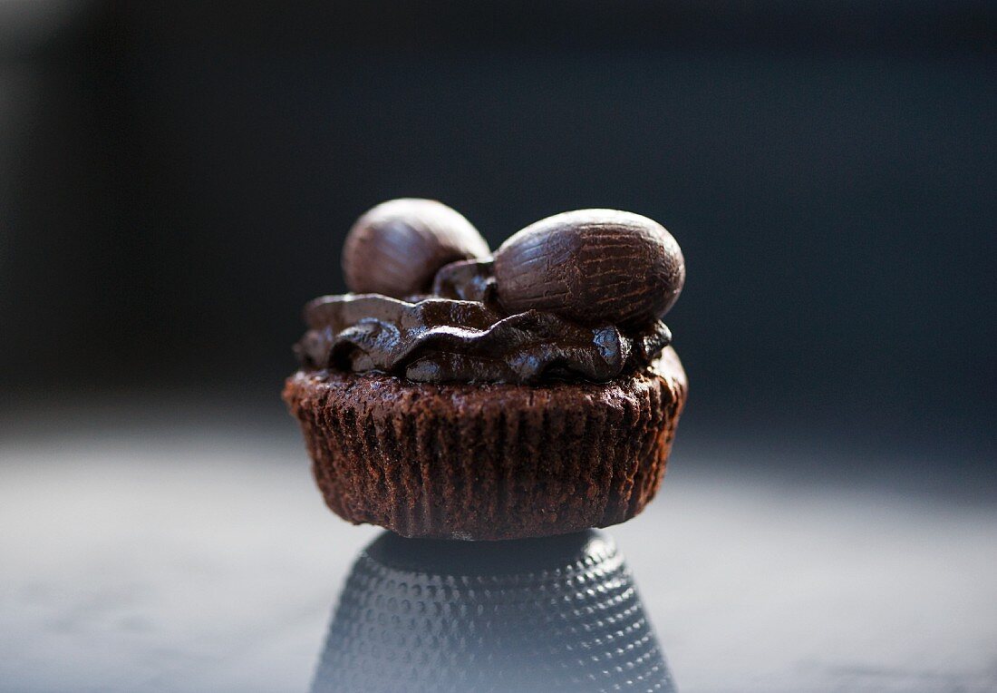 A chocolate cupcake with chocolate frosting and chocolate Easter eggs (close-up)