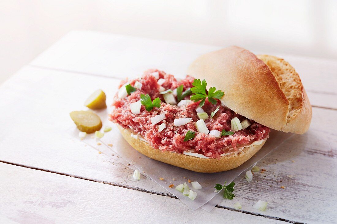 A roll with raw minced meat, onions and gherkins