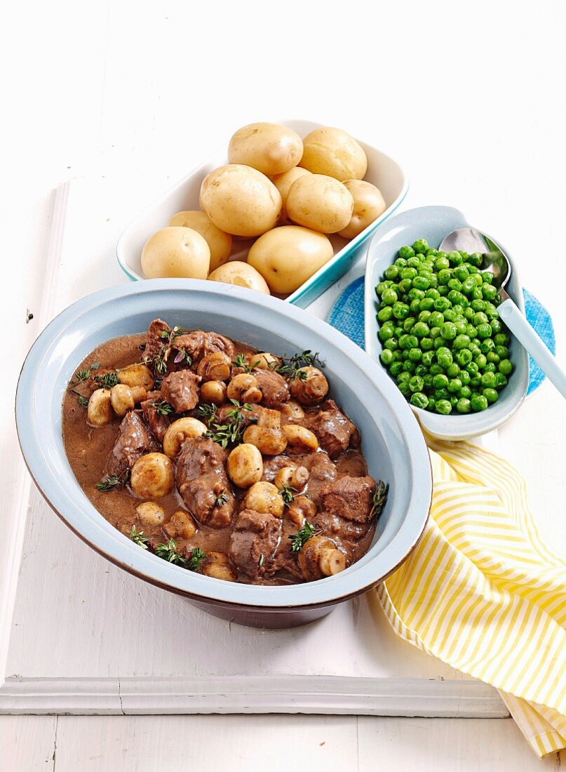 Beef and mushroom ragout from the oven with jacket potatoes and peas