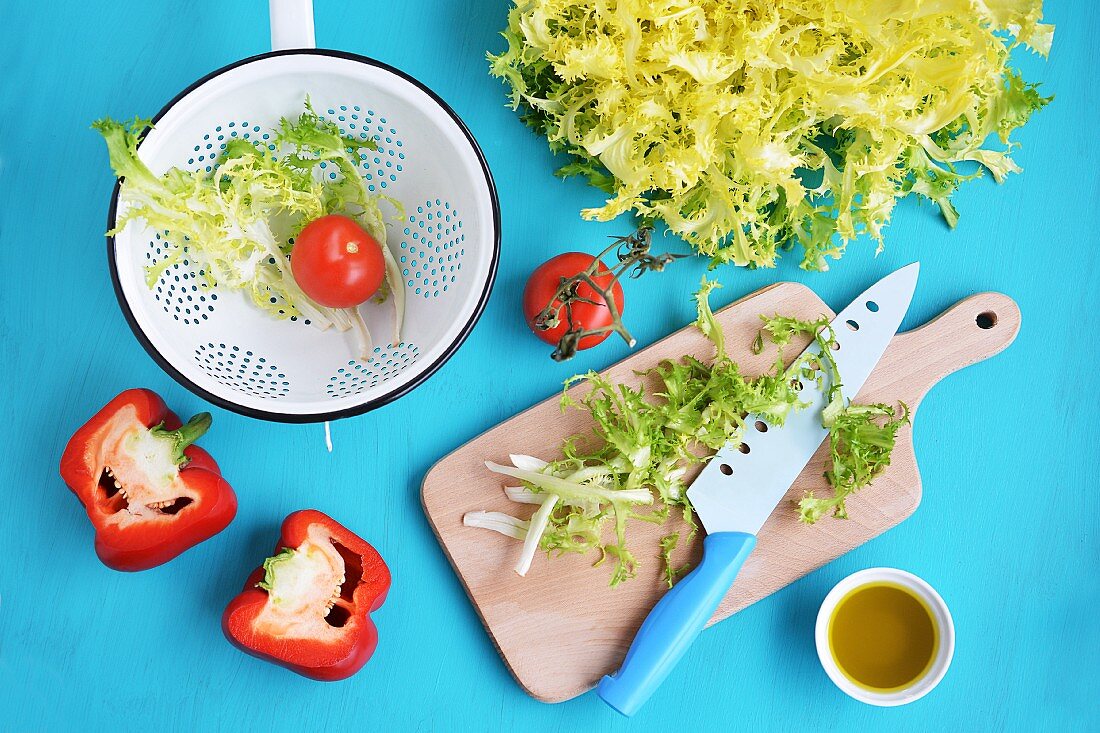 Verschiedene Salatzutaten: Frisee, Tomaten, Paprika und Olivenöl